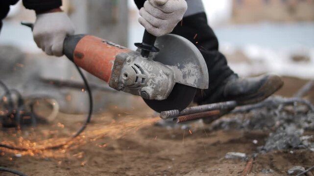 Angle grinder cutting metal rod with sparks at construction site