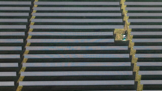 Aerial view of regimented rows of solar panels glinting under the sun, a stark contrast to the surrounding green fields, Sutton Bridge, United Kingdom.