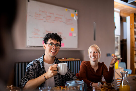 Young friends having coffee and breakfast in a home kitchen