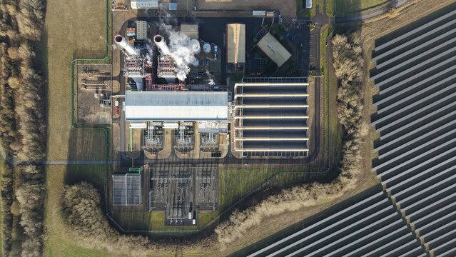 Aerial view of the Sutton Bridge Power Station complex, with smoke billowing from chimneys and solar panels arrayed nearby, Sutton Bridge, United Kingdom.