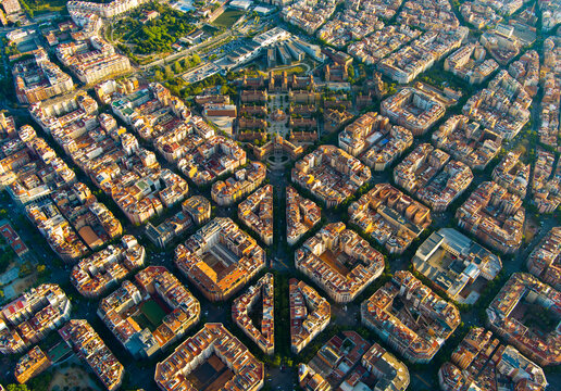 Clean aerial sunrise view of Barcelona highlighting the Eixample grid pattern and dense residential architecture. A striking example of modern urban design in southern Europe