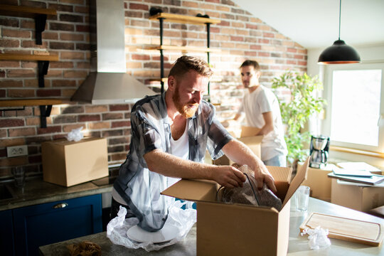 Two men unpacking boxes in new home kitchen