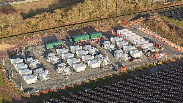 Aerial view of an electrical substation amid the stark landscape, juxtaposed with rows of solar panels, creating a contrast between energy infrastructure and renewable energy, Wisbech, United Kingdom.