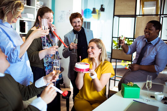 Coworkers celebrate a birthday with cake in a modern office
