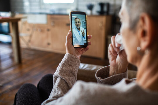 Senior woman on smartphone video call with doctor at home