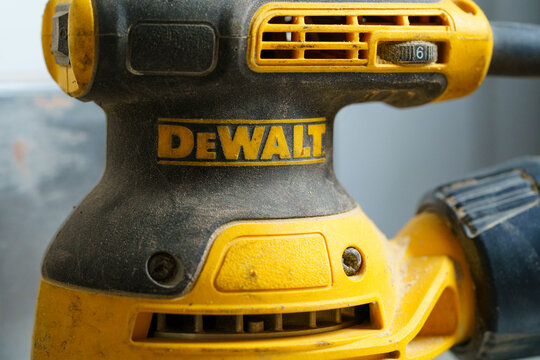 Close up of yellow DeWalt orbital sander power tool with dust on workshop surface