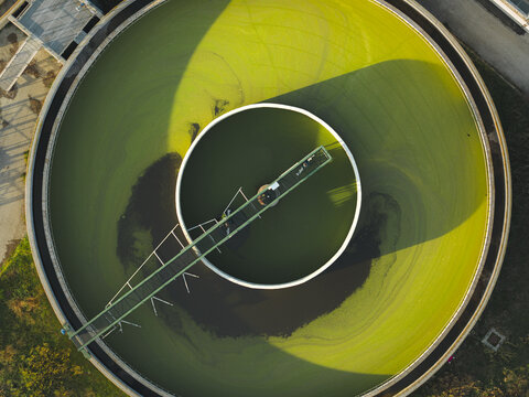 Aerial view of the circular sedimentation tank with green algae and a central mechanism, creating a striking contrast of colors and textures, Rome, Lazio, Italy.
