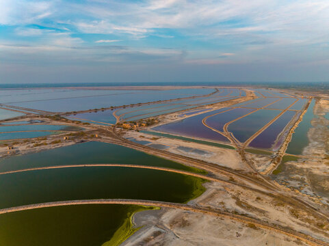 Aerial view of the vast, colorful salt pans reflecting the sky, creating a mosaic of blues, greens, and purples under the expansive sky, Sambhar, Rajasthan, India.