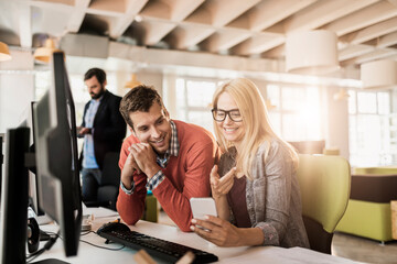 Fototapeta premium Coworkers collaborating with smartphone in modern office