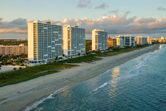 Aerial view of sun-kissed condos lining the sandy beach contrasting with the deep blue sea under a pastel sky, Deerfield Beach, Florida, United States.