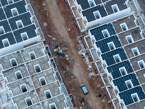 Aerial view of orderly rows of houses with contrasting roof colors lining a textured pathway under construction, Tias, Lanzarote, Canary Islands.