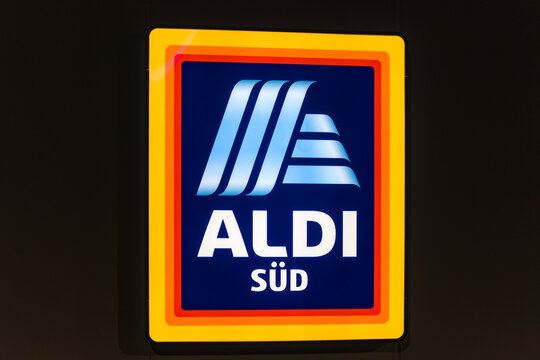 The illuminated blue and orange ALDI S&Uuml;D logo is mounted on the facade of a building during the evening in Leutenbach, Germany.