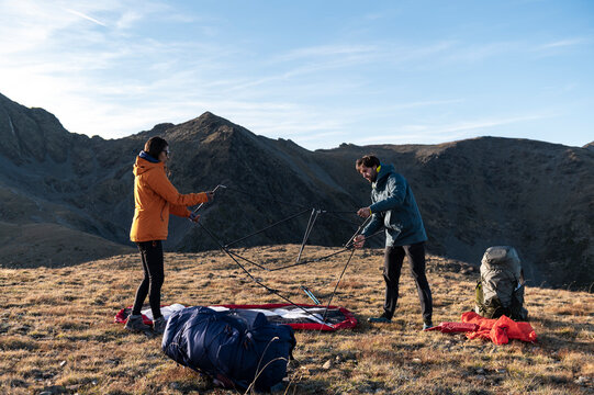 Adventurous hikers assembling shelter before nightfall in mountains