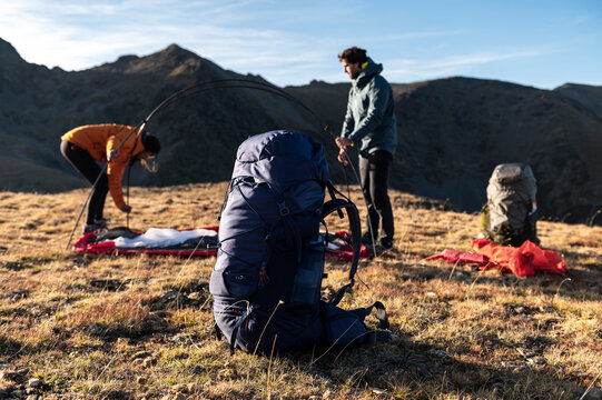 Focused campers building shelter with technical gear in mountains