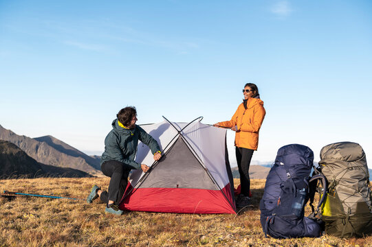 Relaxed outdoor lifestyle as hikers pause during tent assembly