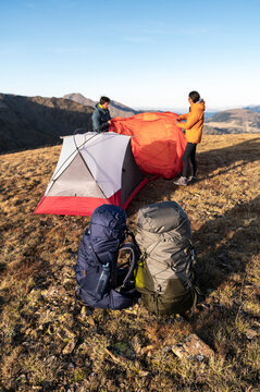 Adventurous campers adding rainfly before night in mountains