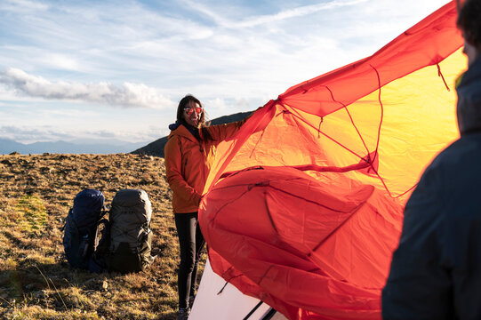 Female camper controlling bright rainfly during alpine setup