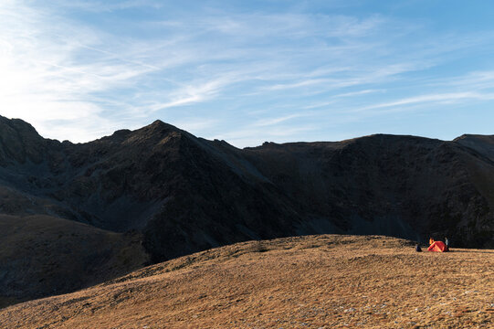 Wide alpine ridge framing friends setting camp before nightfall