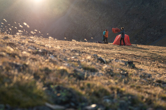 Hiking couple shaking sleeping bags as wind moves across plateau