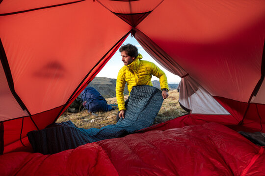Determined hiker positioning inflatable sleeping pad inside tent