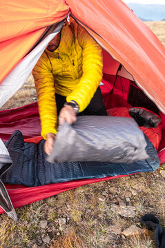 Modern hiker setting inflatable pad for comfort at camp