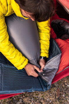 Hands adjusting inflatable sleeping pad for overnight comfort