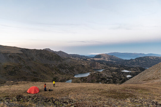 Hikers preparing camp in vast alpine environment at twilight