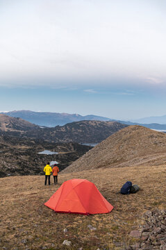 Wide alpine panorama with hikers and tent in distance