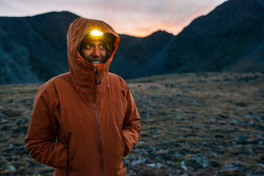 Smiling hiker wearing headlamp during cold mountain evening