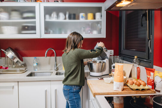 Young girl learning baking skills in kitchen with mixer
