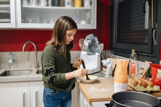 Young girl preparing ingredients for baking cake in kitchen