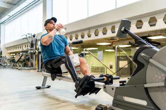 Man with prosthetic leg hydrating during gym training