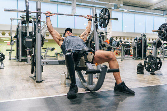 Man with prosthetic leg doing bench press in gym