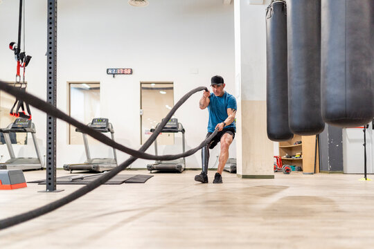 Man with prosthetic leg training with battle ropes at a gym