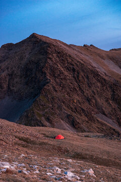 Alpine cirque surrounding small tent beneath pastel twilight