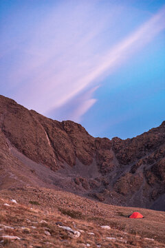 Remote alpine slope with solitary tent under fading sky