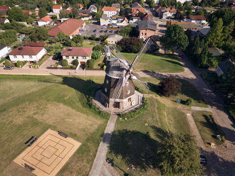 Aerial view of a historic windmill standing proudly on a lush green field, its sails reaching for the sky, Woldegk, Mecklenburg-Vorpommern, Germany.