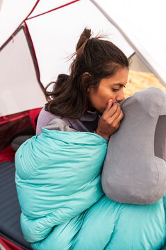 Weekend adventurer preparing inflatable pillow sitting in sleeping bag inside tent