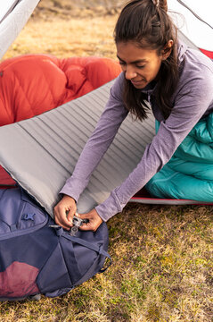Female camper deflating sleeping pad inside tent after night rest