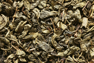 Loose green tea leaves closeup. Dried tea leaf texture background. Natural tea ingredient detail. Herbal tea leaves pattern. Organic dried leaves surface. Tea preparation concept.