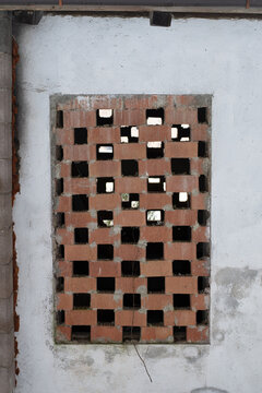 Traditional brick ventilation grid on an old farmhouse wall. Close up of a rustic geometric pattern made of red bricks in a rural Italian building, typical architecture of Northern Italy on mountain.