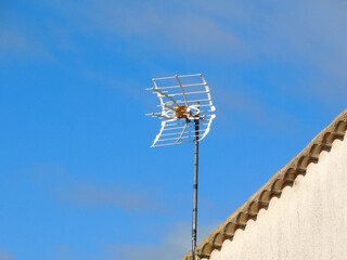 Old Television Antenna on a Rooftop Against Blue Sky