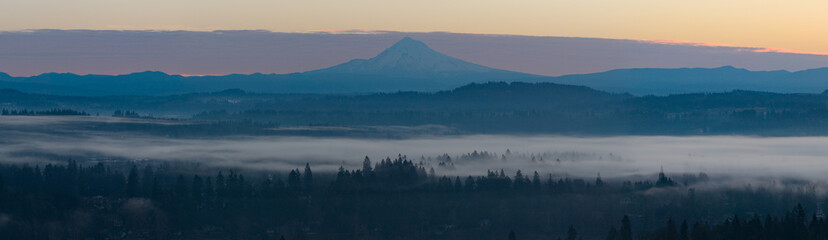 The scenic Mount Hood rises from the forested landscape of northern Oregon. This iconic Pacific Northwest mountain is part of the Cascade Mountain Range.