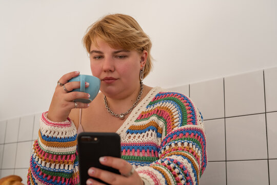 Woman drinking coffee and using smartphone 
