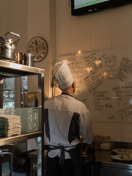 Chef Reviewing Menu Details in a Busy Kitchen During Service Hours