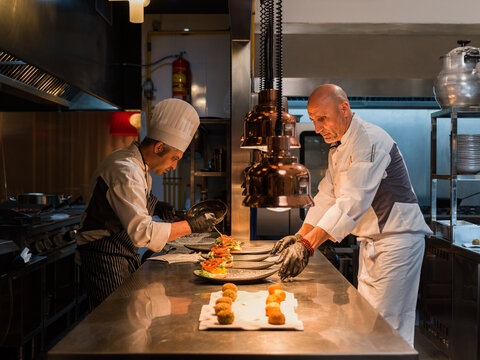 Chefs Skillfully Plating Exquisite Dishes in a Busy Kitchen Setting