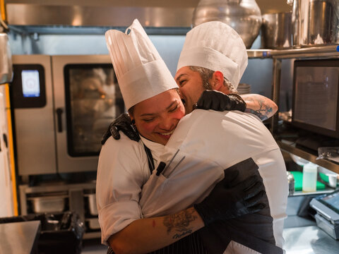 Chefs hugging in kitchen 