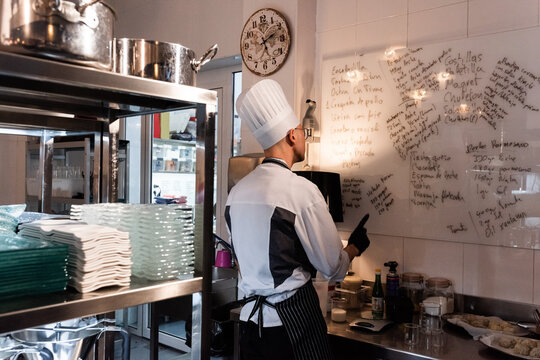 Chef Reviews Menu Preparations in Busy Kitchen Setting