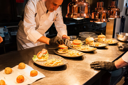 Chefs Preparing Gourmet Burgers With Fries in a Modern Kitchen Setting