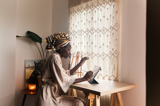 Young Woman Using Tablet by the Window During Daylight Hours